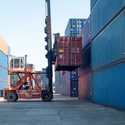 Forklift handling cargo containers at a commercial shipping terminal